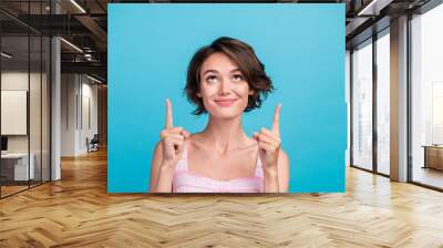 Photo of cute millennial sales manager lady indicate look up wear pink top isolated on blue color background Wall mural