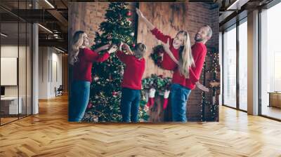 Photo of dad mom and two children spending x-mas morning together pretending air flight hanging garland baubles on newyear tree indoors wear red sweaters Wall mural