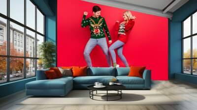 Photo of dreamy inspired couple dance have x-mas fun wear ugly sweater jeans shoes isolated red color background Wall mural