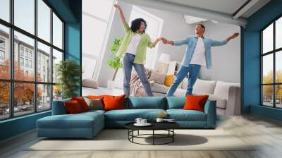 Photo of excited funky couple dressed casual outfits having fun together dancing indoors house room Wall mural