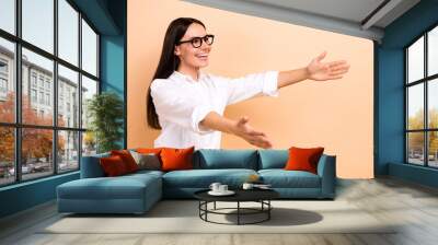 Photo of excited funny woman dressed white shirt eyewear holding arms big empty space isolated beige color background Wall mural