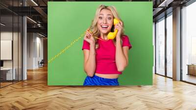 Photo of excited positive laughing girlish young lady positive hold cable yellow vintage phone calling friend isolated on green color background Wall mural