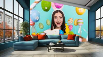 Photo of funky excited lady dressed striped pullover hare headband holding colorful easter eggs isolated teal color background Wall mural