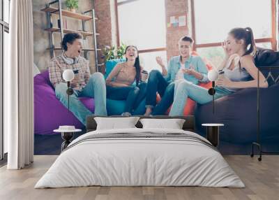 Photo of funny funky workers group sitting dorm bean bags drinking beverages laughing indoors workplace workshop Wall mural