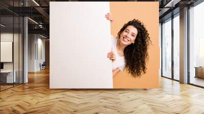 Photo of funny lady holding big white placard presenting novelty information charming promoter wear white clothes isolated beige pastel color background Wall mural