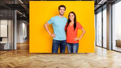 Photo of funny lovely two people couple guy and lady hugging hands by sides one best team wear casual blue orange t-shirts jeans isolated over yellow color background Wall mural