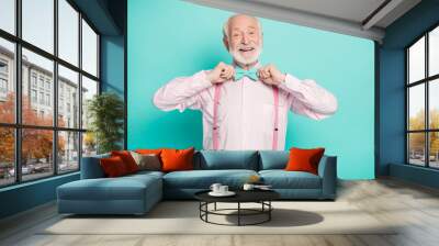 Photo of funny stylish look grandpa hold hands buttoning necktie positive emotions wear pink shirt suspenders bow tie pants isolated bright teal color background Wall mural