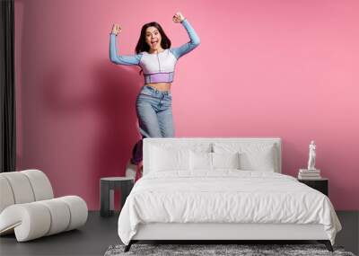 Photo of glad crazy cute girl wear blue trendy clothes hand fist yes empty space isolated on pink color background Wall mural