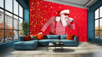 Photo of grandpa grey beard hold mic open mouth scream sing song karaoke wear santa claus x-mas costume suspenders sunglass striped shirt cap isolated red color background Wall mural