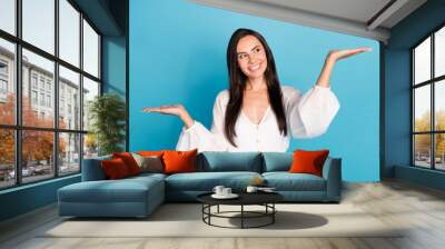 Photo of impressed brunette lady hold arms look promo wear white shirt isolated on blue color background Wall mural