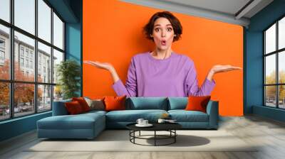 Photo of impressed funky lady wear violet sweatshirt showing arms scales empty space isolated orange color background Wall mural