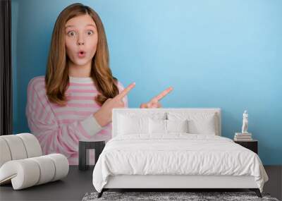 Photo of impressed small girl indicate promo wear pink shirt isolated on blue color background Wall mural