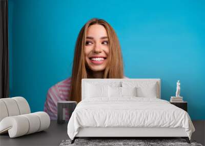 Photo of lovely cheerful nice woman wear stylish striped pink clothes look empty space isolated on blue color background Wall mural