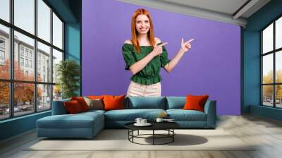 Photo of lovely orange hair millennial lady point empty space wear green open shoulders blouse isolated on violet color background Wall mural