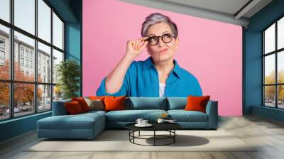 Photo of lovely pensioner lady look skeptical empty space touch specs dressed stylish blue garment isolated on pink color background Wall mural