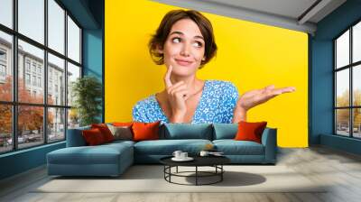 Photo of minded cute girl with bob hair dressed print blouse look empty space palm show object isolated on yellow color background Wall mural