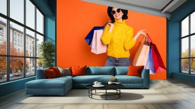 Photo of nice charming girl attractive joyful girl having just ended up shopping and being overjoyed and cheerful while isolated with orange background Wall mural