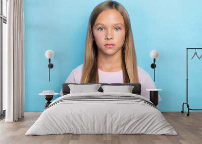 Photo of nice lovely school girl with straight hairstyle wear white t-shirt serious looking at camera isolated on blue color background Wall mural