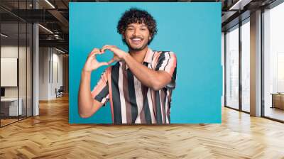 Photo of nice young man show heart symbol wear shirt isolated on teal color background Wall mural