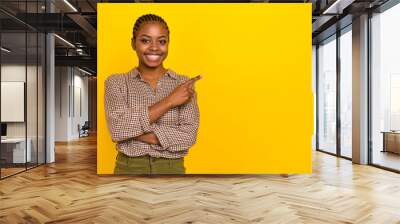 Photo of positive cheerful woman wear plaid shirt smiling pointing empty space isolated yellow color background Wall mural