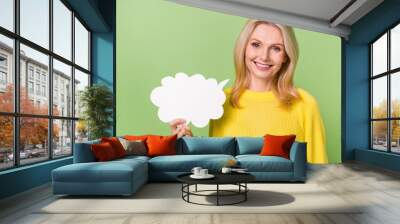 Photo of positive lady hold paper mind cloud banner advertise information wear sweater isolated green color background Wall mural