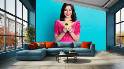 Photo of positive millennial girl using smart gadget writing email forum friend isolated blue color background Wall mural