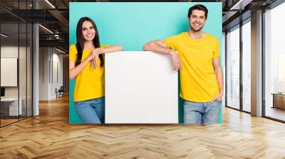 Photo of positive sweet married couple wear yellow t-shirts holding placard empty space isolated teal color background Wall mural