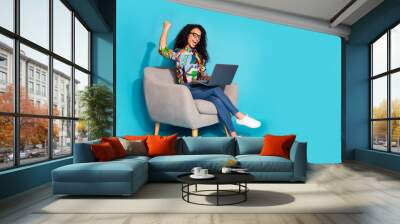 Photo of pretty cute cheerful woman wear stylish clothes sit armchair pass exam yes netbook isolated on blue color background Wall mural