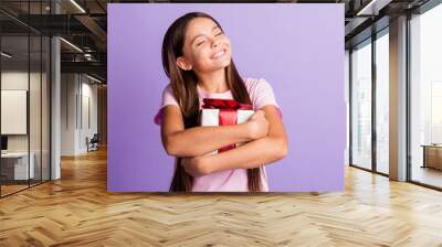 Photo of pretty dreamy schoolgirl dressed pink t-shirt hugging embracing present box isolated purple color background Wall mural