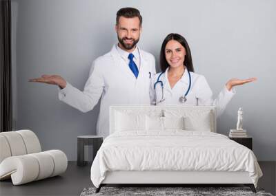 Photo of pretty happy two doctors wear white coats comparing arms empty space hugging isolated grey color background Wall mural