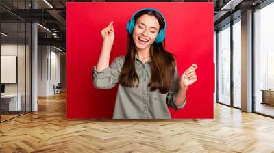 Photo of pretty lady cheerful mood modern technology headphones on ears listen new popular youth song wear casual grey green shirt isolated red color background Wall mural