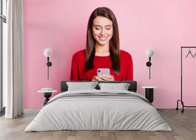 Photo of pretty young lady hold telephone look screen white smile wear red sweater isolated pink color background Wall mural