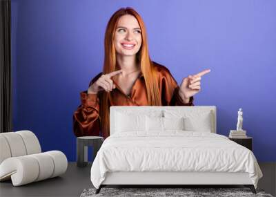 Photo of pretty young woman indicate fingers empty space wear brown shirt isolated on violet color background Wall mural