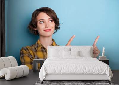 Photo of promoter girl direct finger empty space look up wear checkered shirt isolated blue color background Wall mural