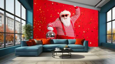 Photo of retired old man grey beard hold vintage disco ball dance funky wear santa x-mas costume suspenders sunglass gloves striped shirt cap isolated red color background Wall mural