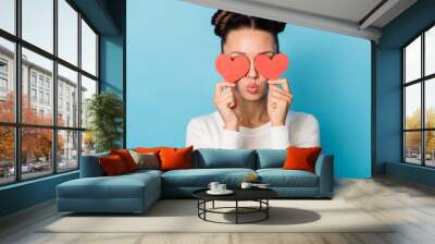 Photo of romantic girl hide eyes red paper hearts blow air kiss wear white sweater isolated blue color background Wall mural