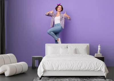 Photo of shiny charming lady dressed checkered shirt jumping high showing thumbs up isolated purple color background Wall mural