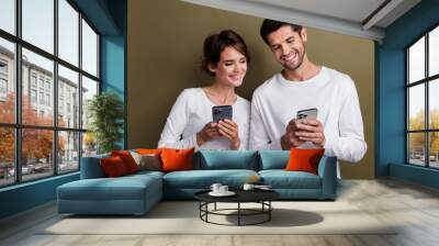 Photo of shiny cheerful married couple wear white shirts online reading messages modern gadgets isolated brown color background Wall mural