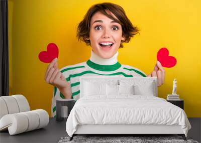 Photo of shiny excited lady wear striped pullover holding two small red hearts isolated yellow color background Wall mural