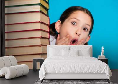 Photo of small schoolchild open mouth pile stack book wear uniform isolated on blue color background Wall mural