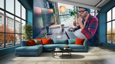 Photo of smart intelligent coder dressed hat glasses writing application software modern gadget indoors workplace workstation loft Wall mural