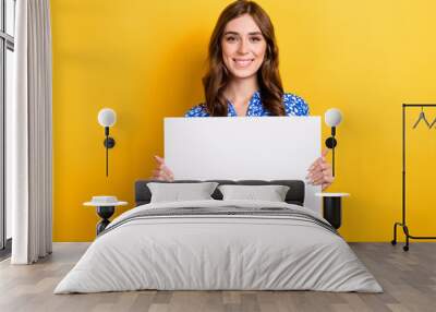 Photo of sweet cheerful woman dressed blue blouse holding white placard empty space isolated yellow color background Wall mural