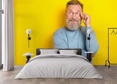 Photo of thoughtful funky man pensioner dressed blue pullover arm eyewear looking empty space isolated yellow color background Wall mural