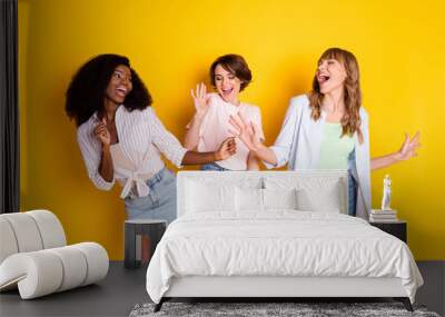 Photo of three charming excited positive girls enjoy free time vacation disco isolated on yellow color background Wall mural