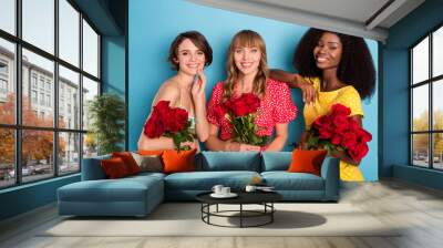 Photo of three young girls happy positive smile adorable hold flower bouquets spring holiday isolated over blue color background Wall mural