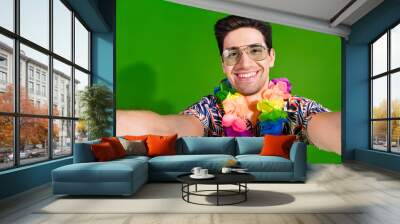 Photo of toothy beaming nice guy with bristle dressed print shirt in glasses necklace making selfie isolated on green color background Wall mural