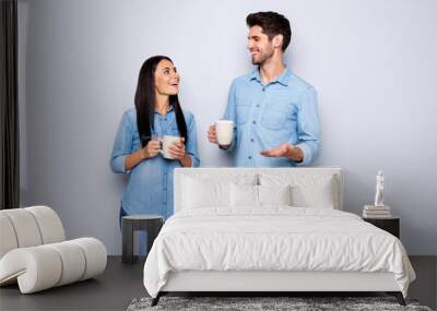 Photo of two amazing colleagues working together spend coffee break chatting holding hot beverage wear casual jeans clothes isolated grey color background Wall mural