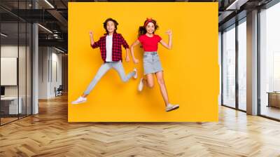 Photo of two crazy children jump fast run wear casual clothes footwear isolated yellow color background Wall mural