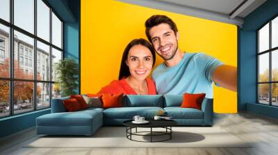 Photo of two funny guy lady people couple making cute selfies recording video for new social network blog wear casual blue orange t-shirts isolated yellow color background Wall mural