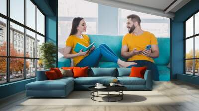 Photo of two young partners sit couch show smart phone free time modern interior apartment indoors Wall mural